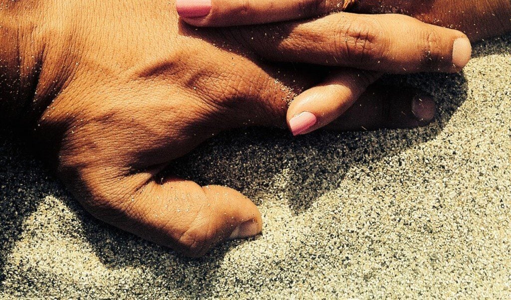 Couple hands in sand