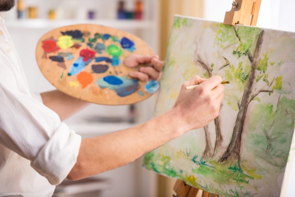 A hand working on a painting.